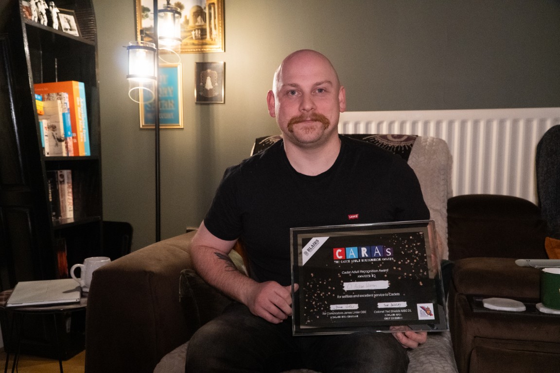 Civilian Instructor Aidan Warren holding his CARAs award